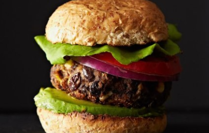 A stack of Black Bean and Corn Burgers on toasted buns with melted cheese and fresh avocado slices