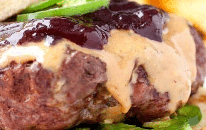 A juicy Peanut Butter Jelly Burger with melted peanut butter and crispy bacon on a toasted bun