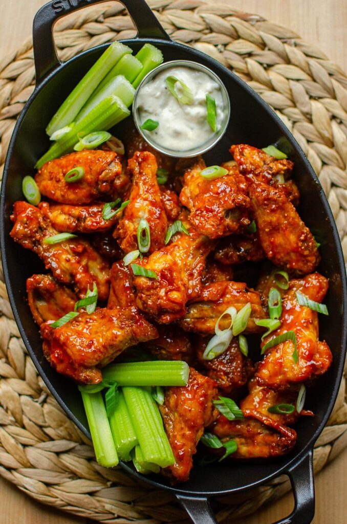 Platter of crispy Buffalo Chicken Wings tossed in spicy red sauce served with celery sticks and blue cheese dip