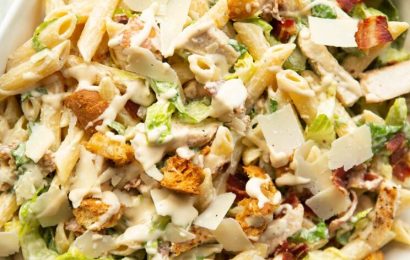 A large pot of creamy white chicken chili topped with fresh cilantro, avocado slices, and a dollop of sour cream on a festive wooden table