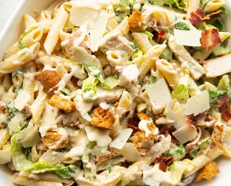 A large pot of creamy white chicken chili topped with fresh cilantro, avocado slices, and a dollop of sour cream on a festive wooden table