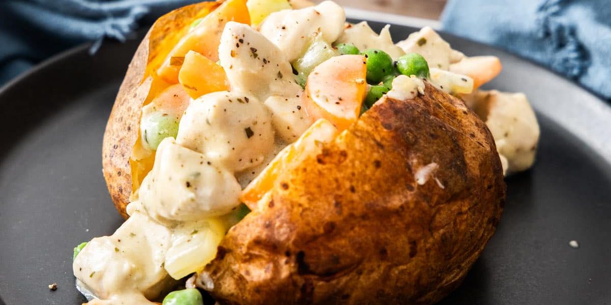 Golden brown Chicken Pot Pie Baked Potato topped with melted cheese and fresh parsley