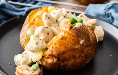 Golden brown Chicken Pot Pie Baked Potato topped with melted cheese and fresh parsley