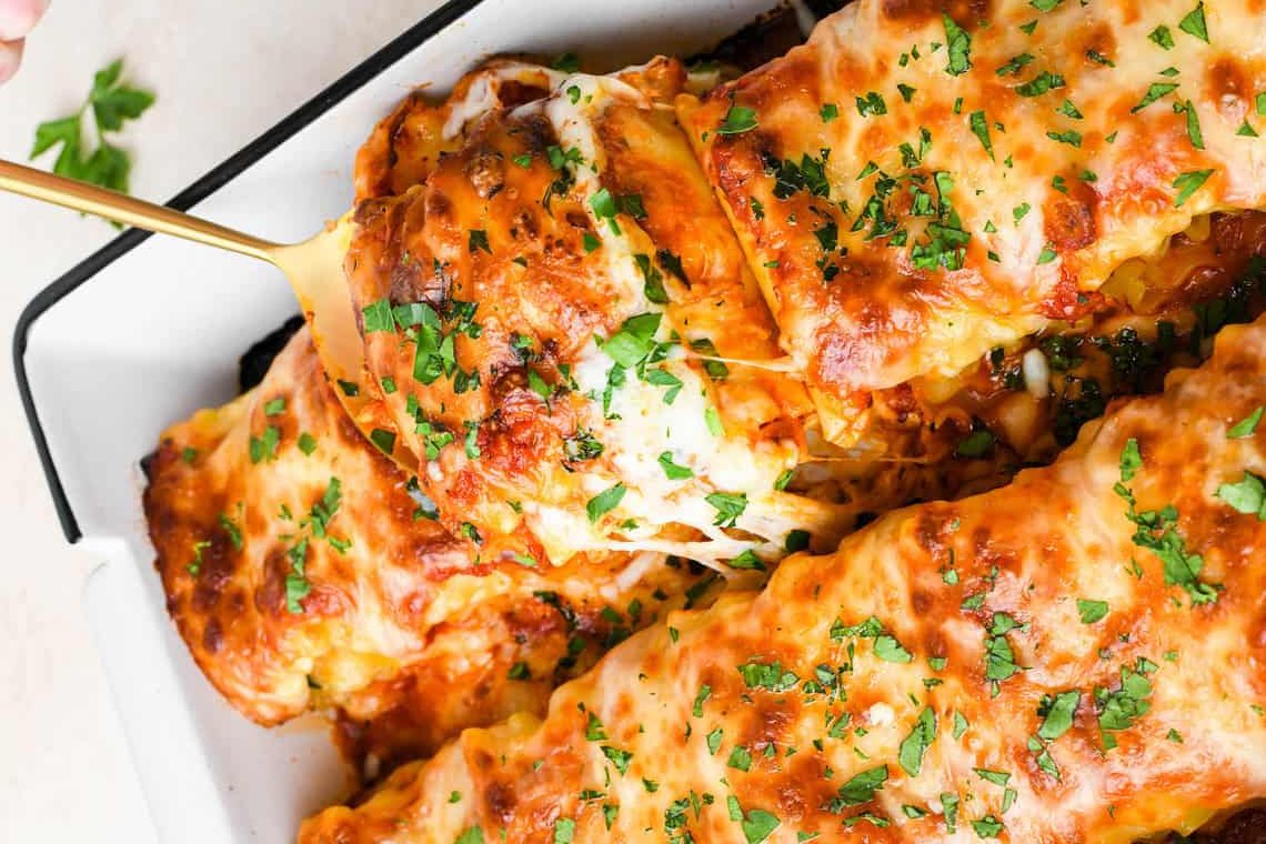 Close-up of creamy chicken lasagna roll-ups with melted mozzarella and sun-dried tomatoes.