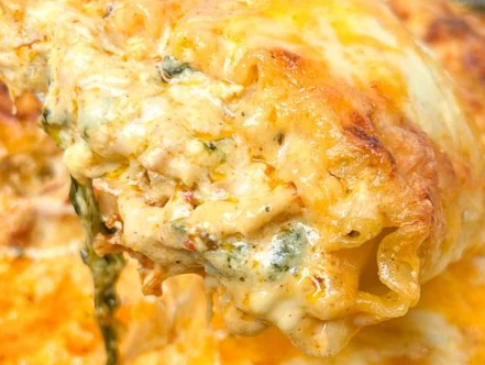 Close-up of creamy chicken lasagna roll-ups with melted mozzarella and sun-dried tomatoes.