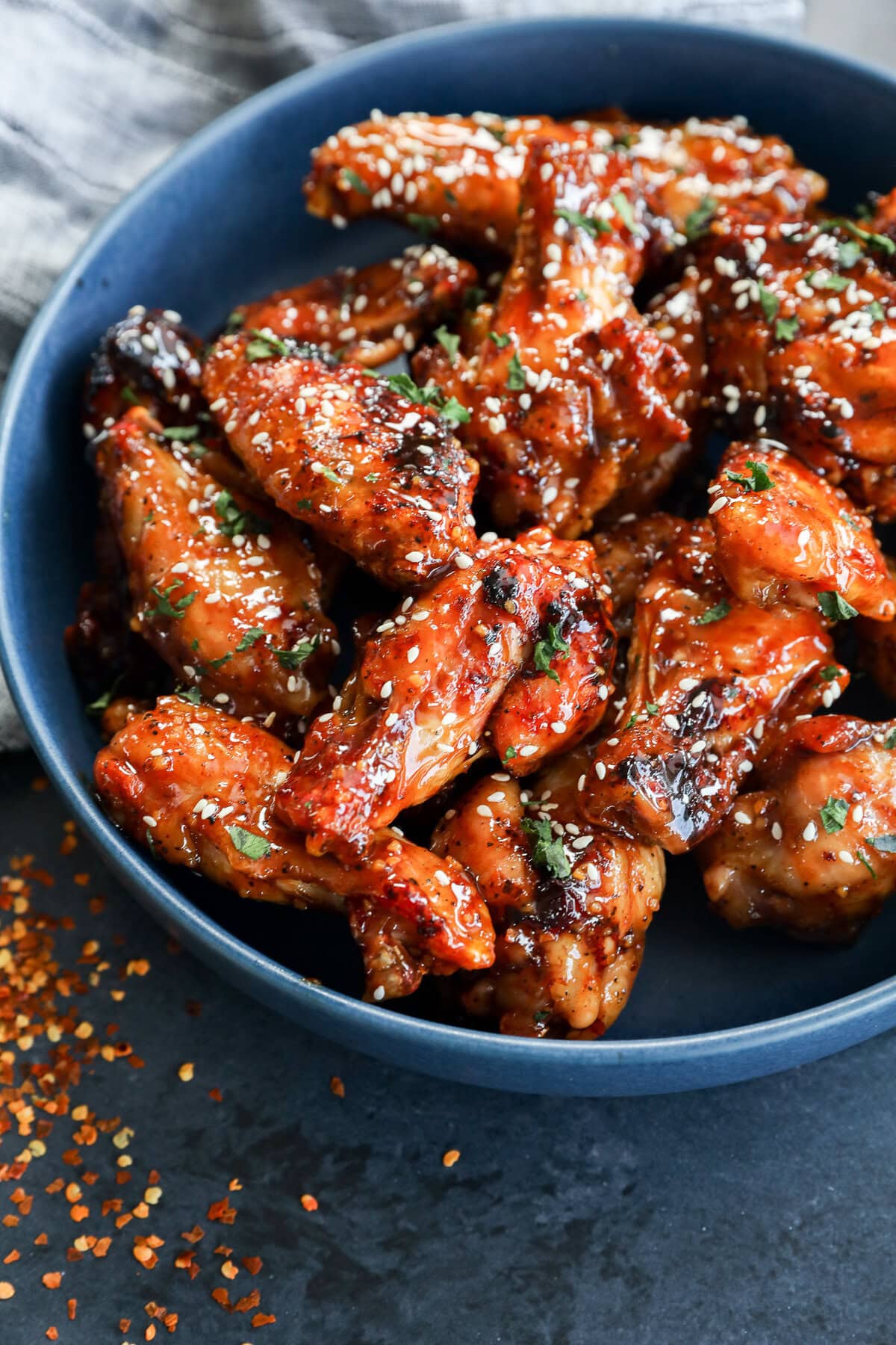 A platter of crispy Honey Garlic Chicken Wings garnished with sesame seeds and green onions.