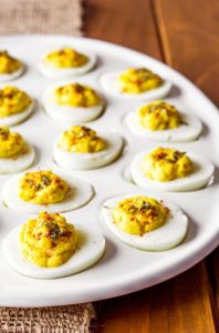 A platter of The Best Deviled Eggs garnished with smoked paprika and fresh green chives