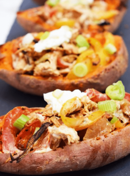 A plate of Creamy Cajun Chicken Stuffed Sweet Potato Skins topped with melted cheese and green onions.