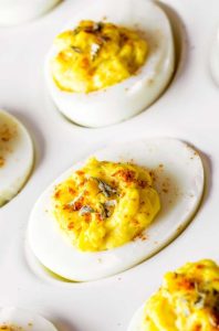 Mixing deviled egg ingredients like mayo and mustard in a bowl until creamy.