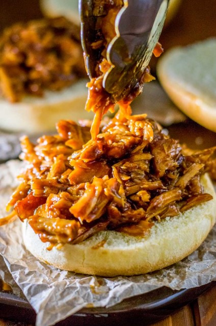Seasoned pork shoulder placed in a slow cooker with apple cider vinegar and broth
