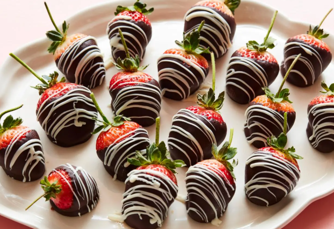 A tray of gourmet homemade chocolate dipped strawberries with white chocolate drizzles and heart sprinkles for Valentine's Day