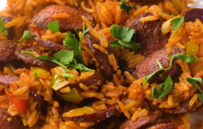 A steaming skillet of Cajun sausage and rice topped with fresh green onions and bell peppers
