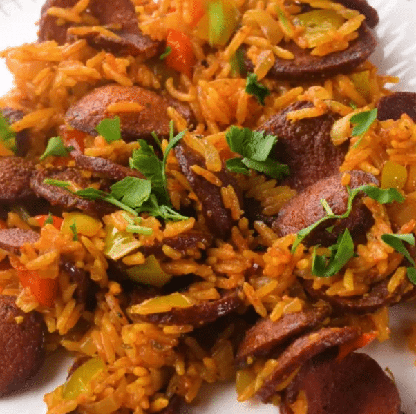 A steaming skillet of Cajun sausage and rice topped with fresh green onions and bell peppers
