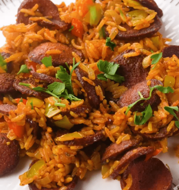 A steaming skillet of Cajun sausage and rice topped with fresh green onions and bell peppers