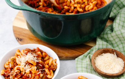 A steaming skillet of classic American Chop Suey featuring tender macaroni pasta, seasoned ground beef, and a rich tomato sauce, topped with melted cheese.