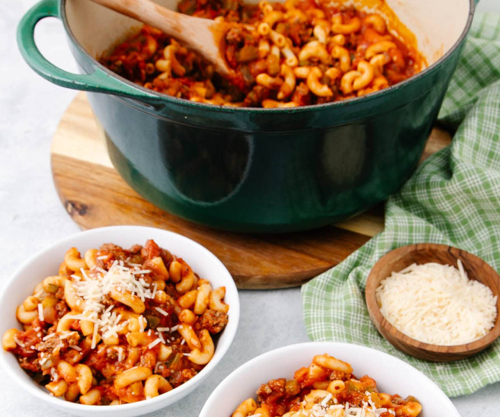 A steaming skillet of classic American Chop Suey featuring tender macaroni pasta, seasoned ground beef, and a rich tomato sauce, topped with melted cheese.