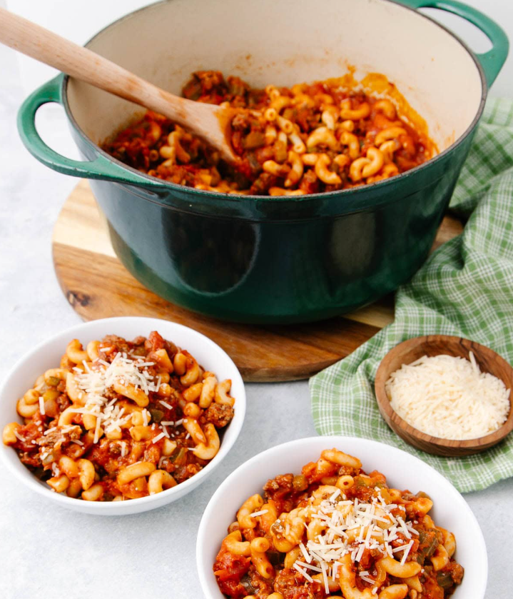 A steaming skillet of classic American Chop Suey featuring tender macaroni pasta, seasoned ground beef, and a rich tomato sauce, topped with melted cheese.
