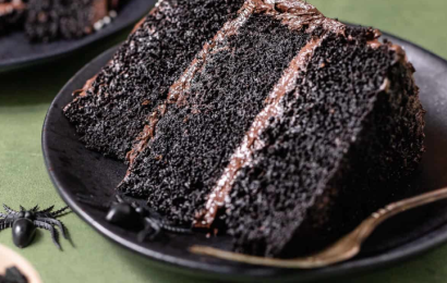 A dramatic sliced black velvet cake with stark white cream cheese frosting, showing the rich, dark black crumb inside.