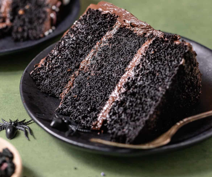 A dramatic sliced black velvet cake with stark white cream cheese frosting, showing the rich, dark black crumb inside.