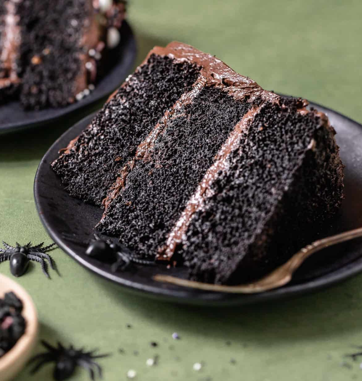 A dramatic sliced black velvet cake with stark white cream cheese frosting, showing the rich, dark black crumb inside.