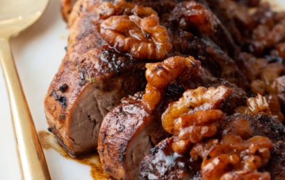 Raw pork tenderloin marinating in a rich, dark bourbon and brown sugar sauce in a ziplock bag.
