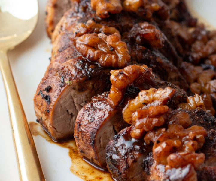 Raw pork tenderloin marinating in a rich, dark bourbon and brown sugar sauce in a ziplock bag.