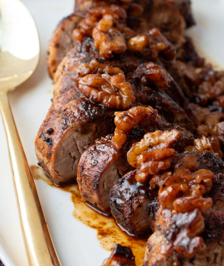 Raw pork tenderloin marinating in a rich, dark bourbon and brown sugar sauce in a ziplock bag.