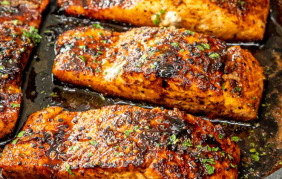 A pan-seared salmon fillet glazed in a glossy honey butter sauce with charred lemon slices and fresh parsley.