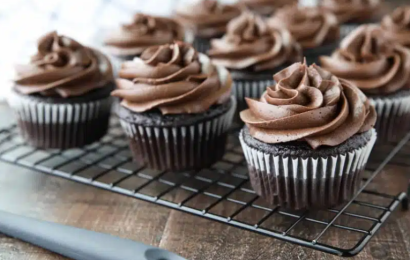 A thick, velvety swirl of rich homemade chocolate cream cheese frosting being piped onto a moist chocolate cupcake.