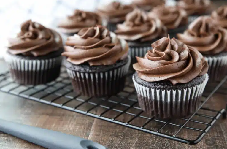 A thick, velvety swirl of rich homemade chocolate cream cheese frosting being piped onto a moist chocolate cupcake.