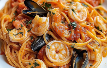 A steaming bowl of classic Italian seafood pasta featuring fresh mussels, clams, shrimp, and linguine tossed in a rich, garlicky tomato sauce on a rustic wooden table.