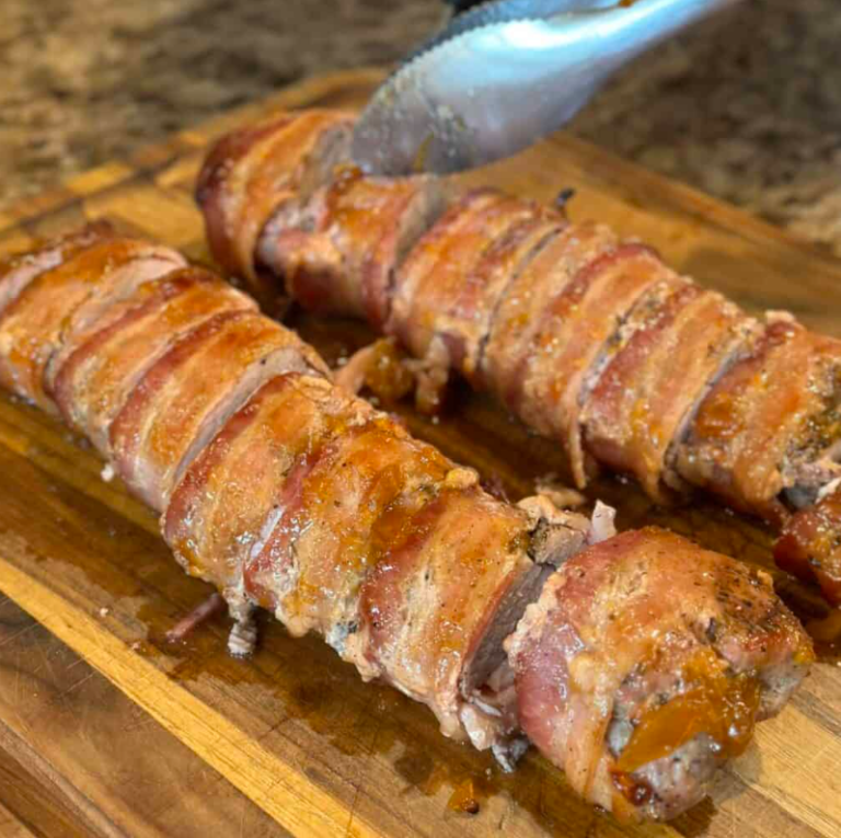 A perfectly sliced juicy roasted pork tenderloin coated in a sticky, golden brown sugar glaze, served on a white serving platter with a sprinkle of fresh parsley.