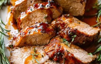 A juicy, sliced honey garlic pork tenderloin glazed in a thick, glossy sweet and savory sauce on a serving platter, garnished with fresh parsley and minced garlic.