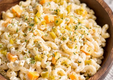 A large glass bowl filled with a creamy Jalapeno Popper Macaroni Salad, topped with crispy chopped bacon, sliced fresh jalapenos, and shredded cheddar cheese.