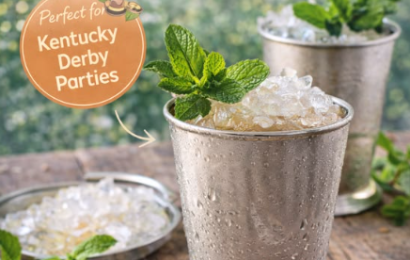 A frosty silver julep cup filled with crushed ice, garnished with a generous bunch of fresh green mint leaves and a straw