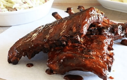 A platter of glossy, sauce-coated grilled chicken wings and drumsticks inspired by famous restaurant flavors.