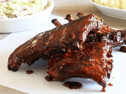 A platter of glossy, sauce-coated grilled chicken wings and drumsticks inspired by famous restaurant flavors.