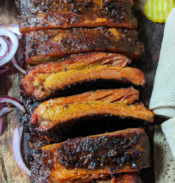 A loaded platter of Tex-Ethiopian BBQ featuring slow-smoked brisket, ribs, and traditional injera bread.