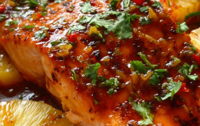 A perfectly baked salmon fillet glazed with a glossy sweet chili sauce, topped with chunks of juicy caramelized pineapple and fresh cilantro.
