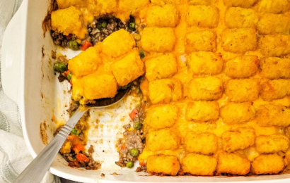 A glass baking dish filled with bubbling hot tater tot casserole with ground beef, melted cheddar cheese, and a golden crispy tater tot topping.