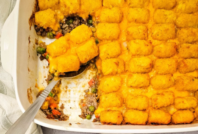 A glass baking dish filled with bubbling hot tater tot casserole with ground beef, melted cheddar cheese, and a golden crispy tater tot topping.
