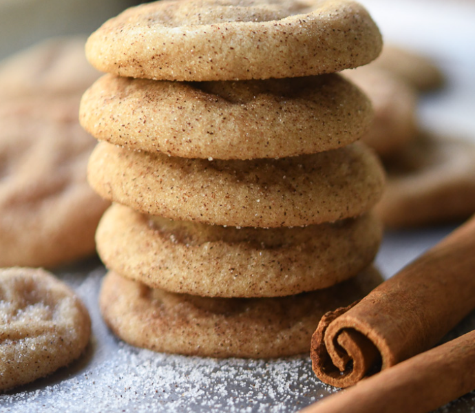 A stack of thick, chewy brown butter snickerdoodle cookies coated in a sparkling layer of cinnamon sugar, showing soft and pillowy centers.