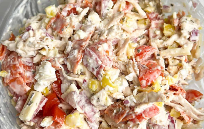 A large mixing bowl filled with creamy Italian grinder chicken salad, loaded with shredded chicken, chopped salami, pepperoncini, and finely shredded lettuce.