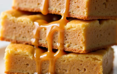A platter of golden-brown, fluffy homemade maple donut bars coated in a thick, shiny maple glaze.