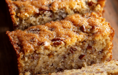 A square slice of moist Sweet Alabama Pecan Bread with a crinkly brown sugar crust and loaded with chopped pecans, served on a vintage ceramic plate.