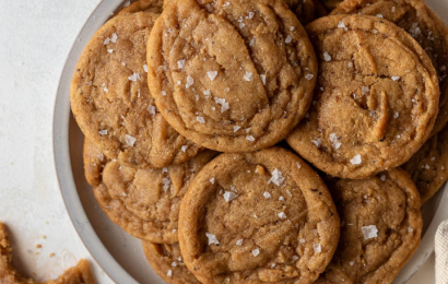 A neat stack of thick, golden-brown chocolate chipless cookies with rippled, crinkly edges and a soft, chewy center on a wire cooling rack.