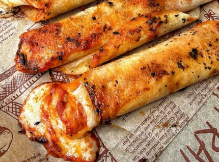A platter of golden-brown, crispy pizza roll ups made with crescent dough, oozing with melted mozzarella cheese and pepperoni slices, served with a bowl of warm marinara sauce.